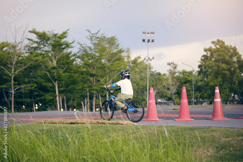 Cute little 7 years old school boy child in safety helmet wearing knee pads, elbow pads and cycling gloves riding a bike on nature, Kid cycling, playing outside at park, Fun exercise for kids