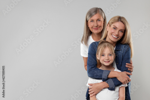 Three generations. Happy grandmother, her daughter and granddaughter on light gray background, space for text