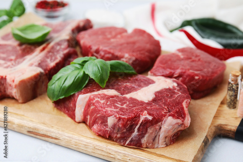 Cut fresh beef meat with basil leaves on wooden board, closeup