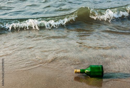 Message bottle on beach in waves