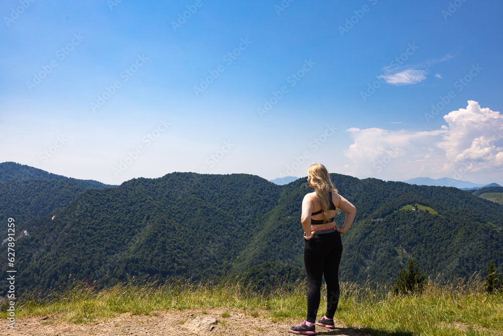 Woman standing on hill and looking at mountains