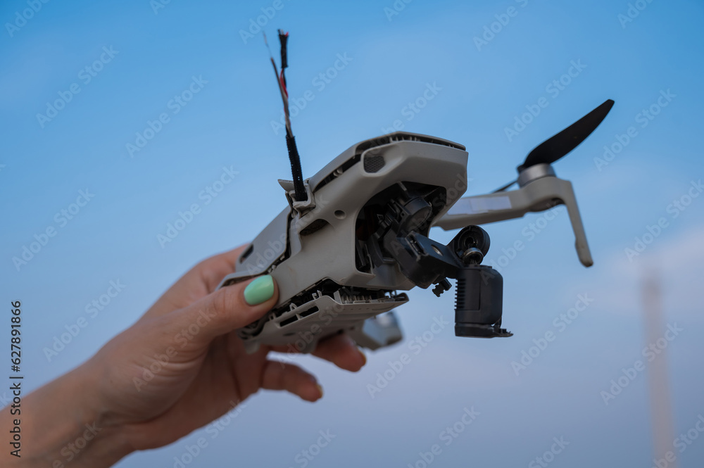 Woman holding crashed drone against blue sky. Woman holding crashed drone against blue sky.