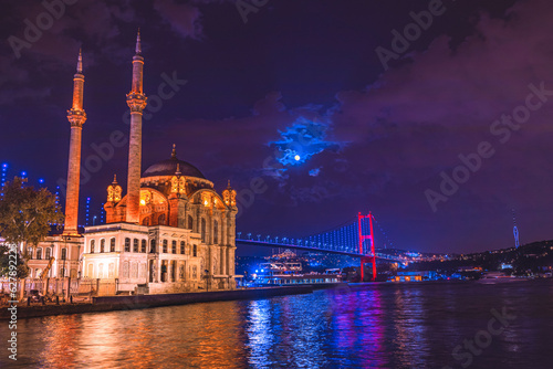 Ortaköy, İstanbul-Mosque and Bosphorus Bridge during blue hour, full moon and blue night Sky. One of the most popular locations on the Bosphorus, Istanbul, Turkey, Selective Focus.