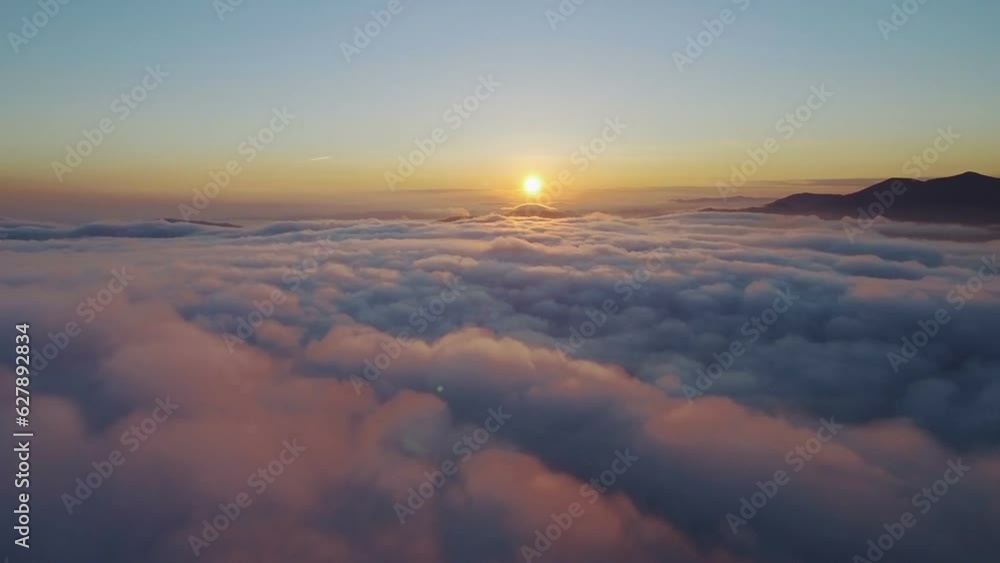 Aerial footage filmed with drone moving through clouds and flying high above the clouds