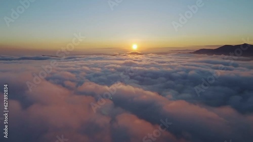 Aerial footage filmed with drone moving through clouds and flying high above the clouds