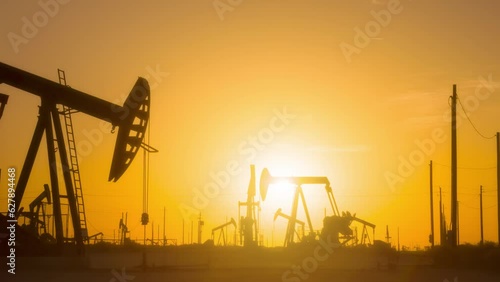 The sun rises behind a large oil field in California.