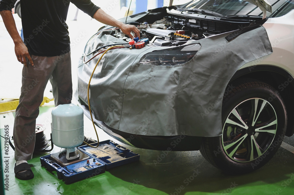 Auto mechanic evacuating and refrigerant recharging the car air conditioning system ,car air