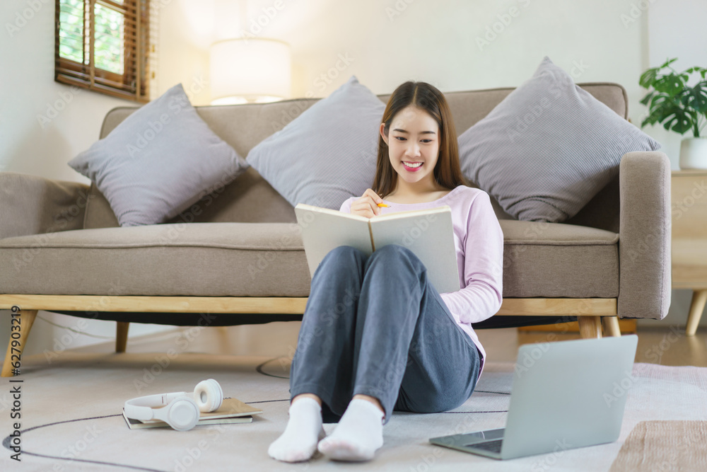 Women thinking about business plan to writing notes while working on laptop in lifestyle at home Women thinking about business plan to writing notes while working on laptop in lifestyle at home