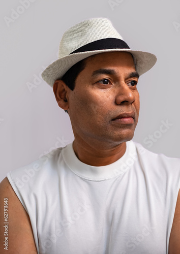 View of a handsome man with white shirt and hat on a light background. Casual man portrait isolated on white background