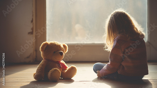 Fotografiet Unhappy cute little girl sitting with a teddy bear