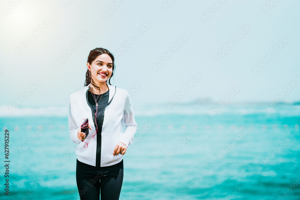 Active young woman smiling while jogging near the sea. Active young woman smiling while jogging near the sea.