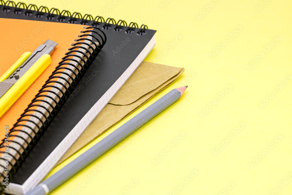 yellow writing desk background with colorful notebooks, pencil, envelope and letter opener yellow writing desk background with colorful notebooks, pencil, envelope and letter opener
