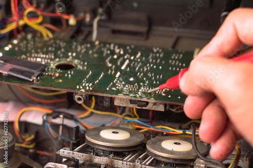 Repairman repairing electronic circuit board with red pen, close-up