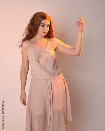 Wall Mural Close up portrait of beautiful brunette  female model wearing a cream dress with golden back light lighting