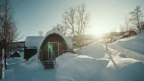 Slow motion panning view of Kirkenes snow hotel in Norway, above the arctic circle. Wooden boutique hotel covered with snow. Beautiful warm sunset. photo