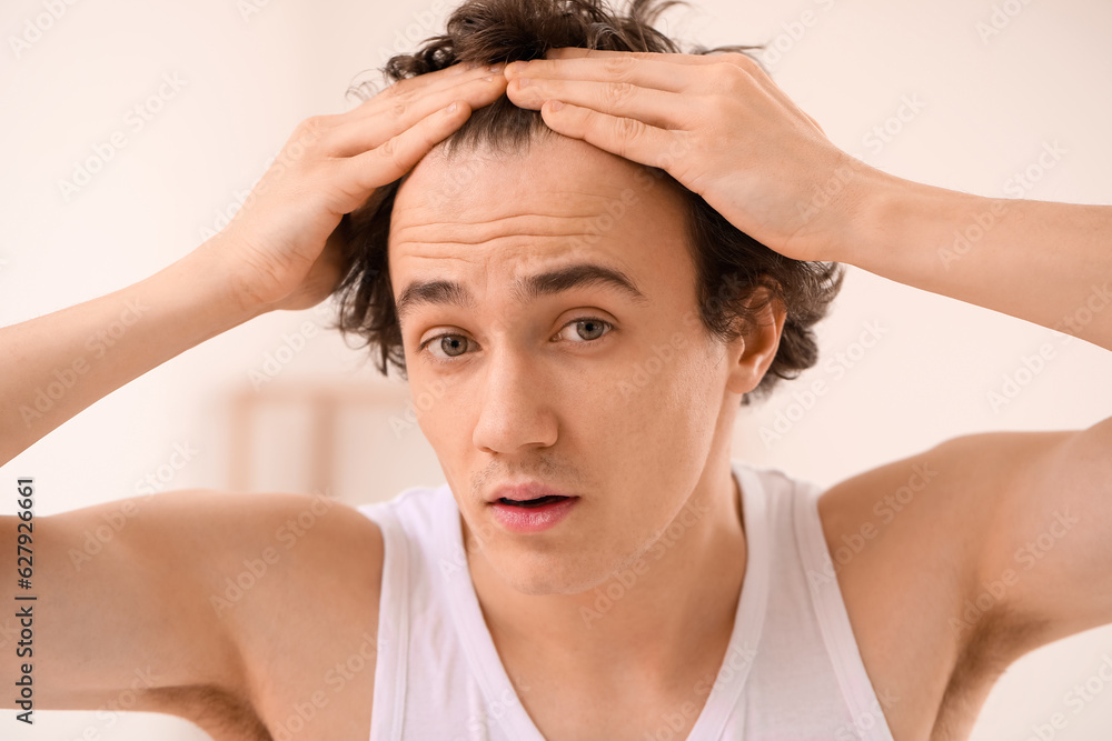 Fototapeta premium Young man with hair loss problem in bathroom, closeup