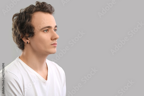 Young man with hair loss problem on grey background, closeup