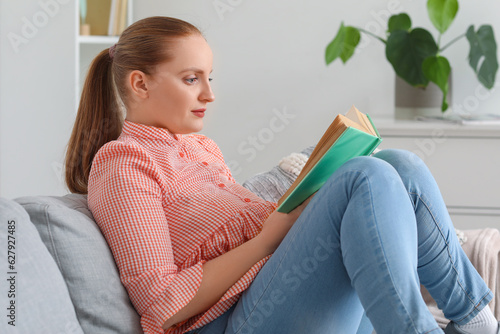 Young woman reading book on...