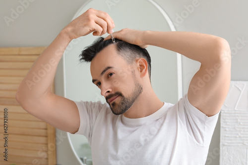 Handsome man using serum fo...