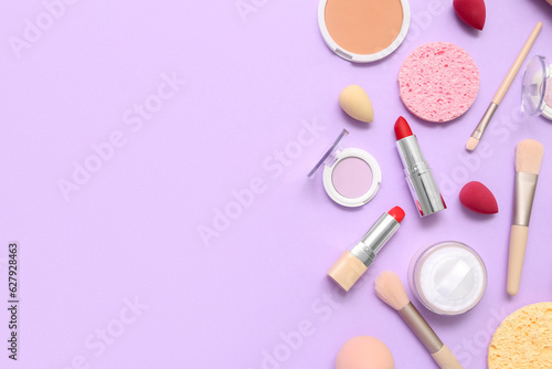 Decorative cosmetics with makeup brushes and sponges on lilac background