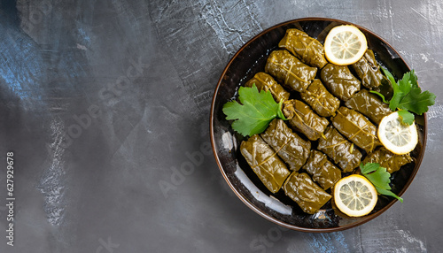 Dolma - stuffed grape leaves with rice and meat on a dark background, view from above, copy space. Traditional Greek, Caucasian and Turkish cuisine photo