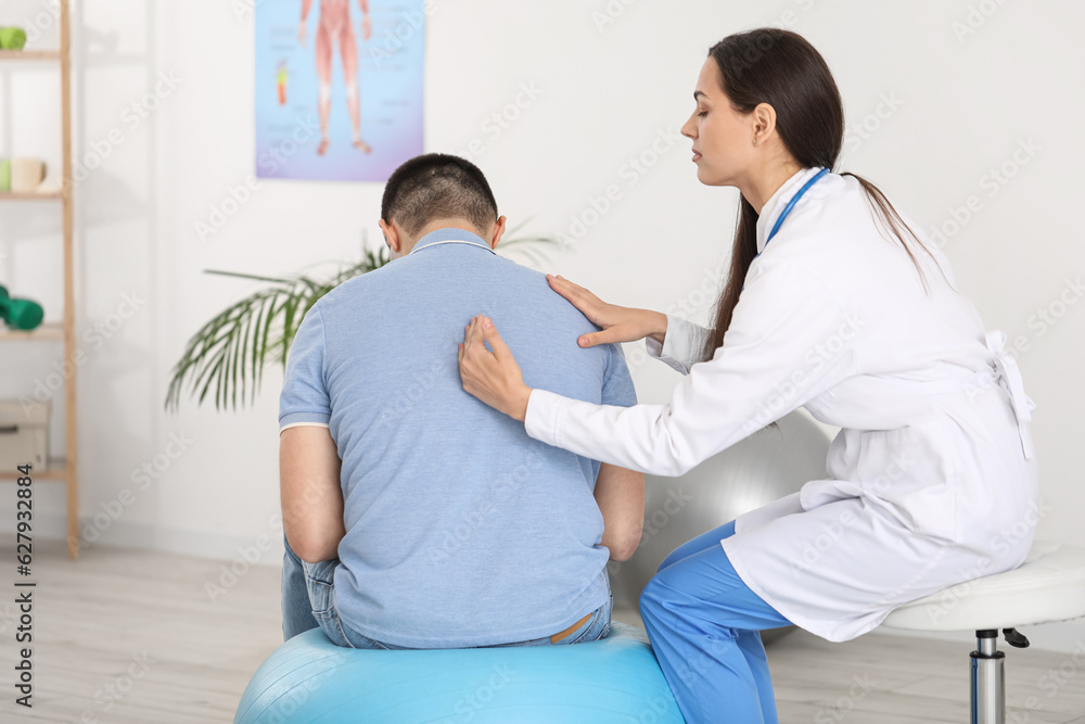 Female doctor checking posture of young man in clinic Female doctor checking posture of young man in clinic