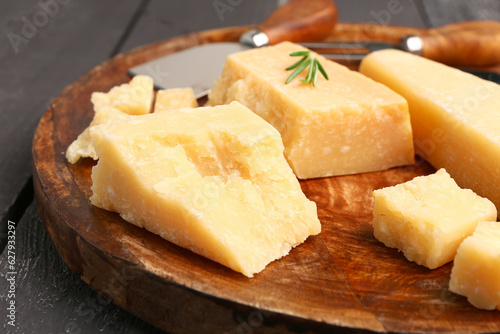 Plate with pieces of tasty Parmesan cheese on dark wooden background