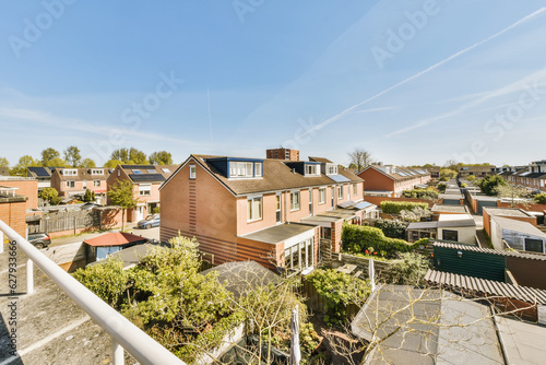 some houses on a sunny day with blue sky and white clouds in the background, as seen from an apartment balcony
