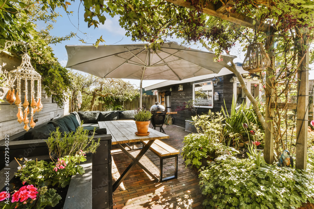 an outdoor living area with patio furniture and umbrellas on the roof, surrounded by lush green plants and flowers