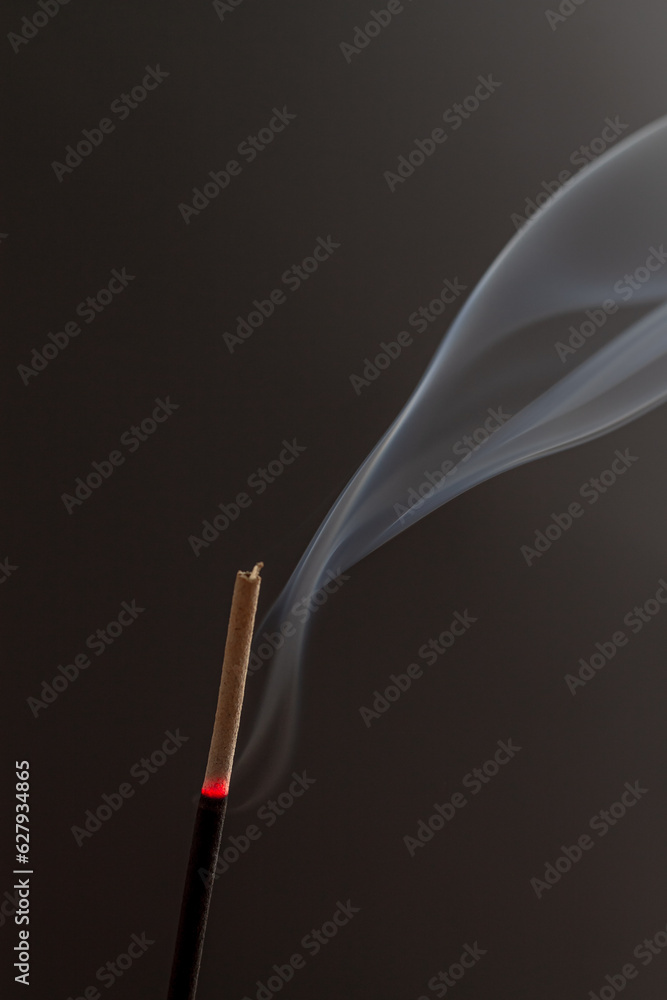 LIT INCENSE ON A BLACK BACKGROUND WITH A TRAIL OF SMOKE LIT INCENSE ON A BLACK BACKGROUND WITH A TRAIL OF SMOKE