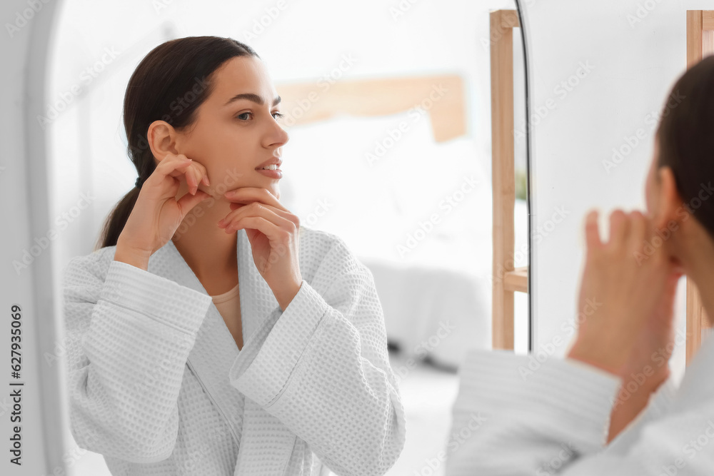 Young woman doing face building exercise near mirror in bathroom Young woman doing face building exercise near mirror in bathroom