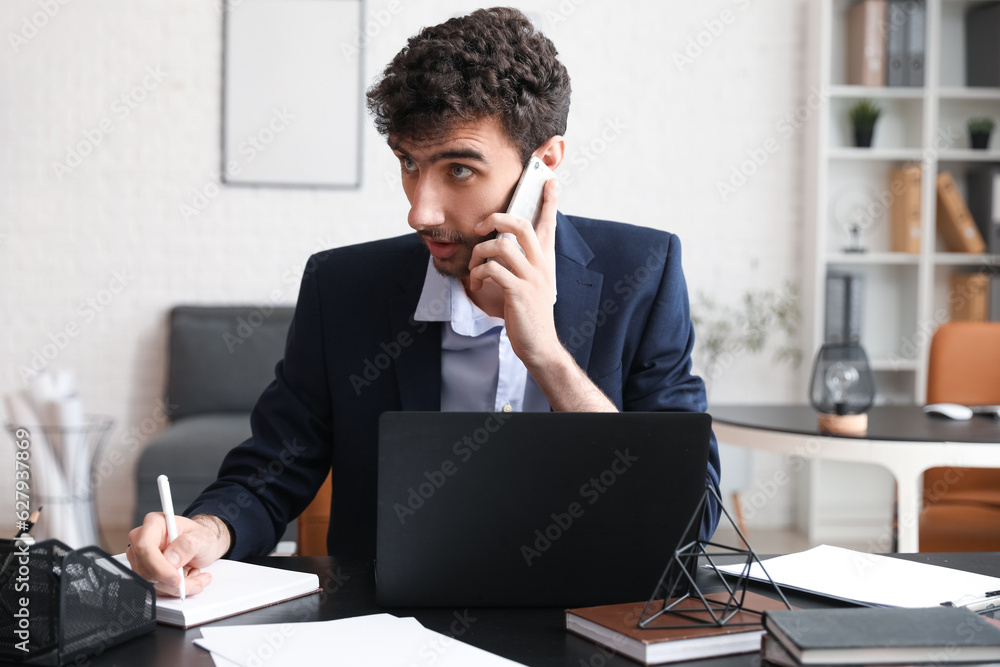 Young businessman working with notebook at table in office Young businessman working with notebook at table in office