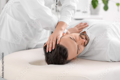 Female physiotherapist working with young man on couch in rehabilitation center, closeup