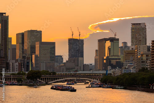 Orange sunset glow over Osaka City with Tenjin Festival boats on river