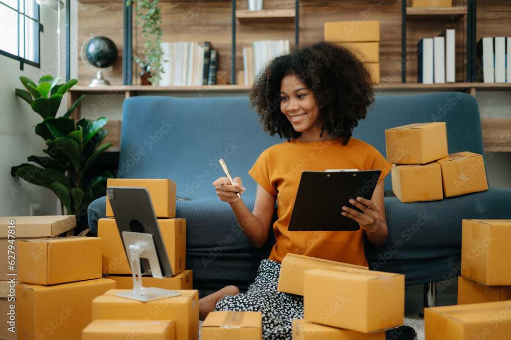 Small business entrepreneur SME freelance African woman working at home office, BOX,tablet and laptop online, marketing, packaging, delivery, e-commerce concept Small business entrepreneur SME freelance African woman working at home office, BOX,tablet and laptop online, marketing, packaging, delivery, e-commerce concept