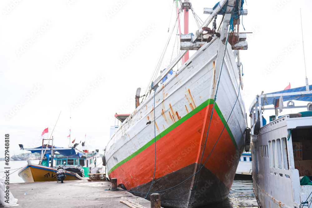 Fototapeta premium Several wooden boats and cargo ships moored at the traditional port while waiting for loading and unloading