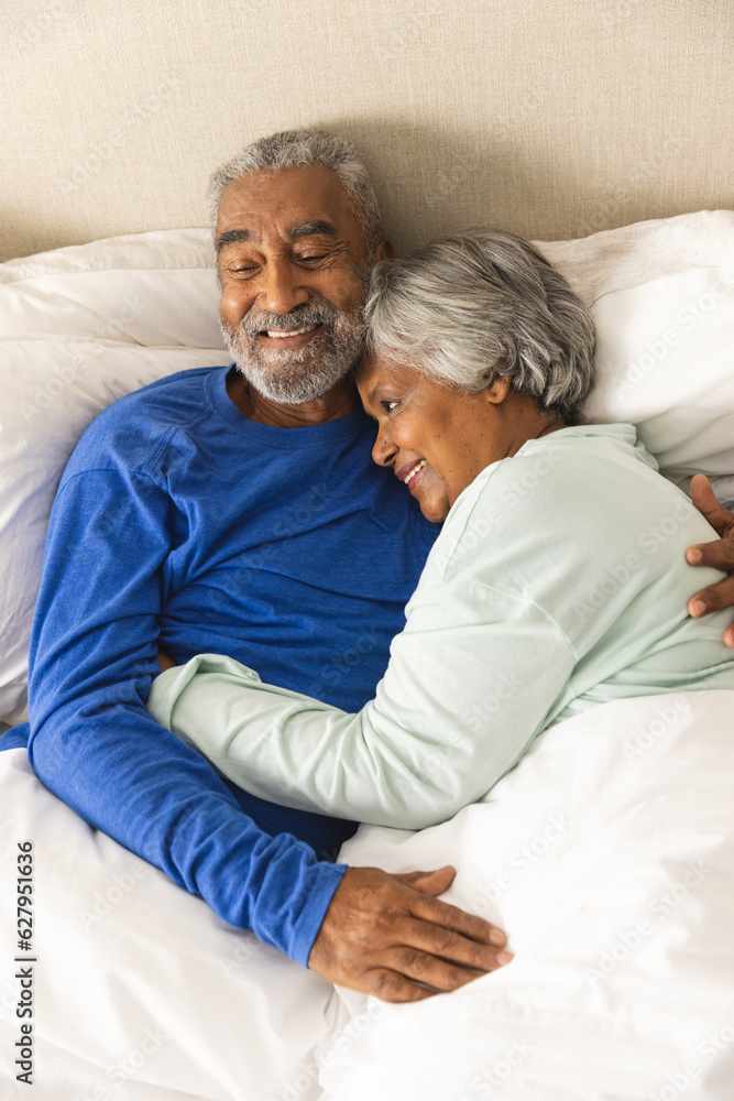 Happy senior biracial couple lying in bed and embracing at home Happy senior biracial couple lying in bed and embracing at home
