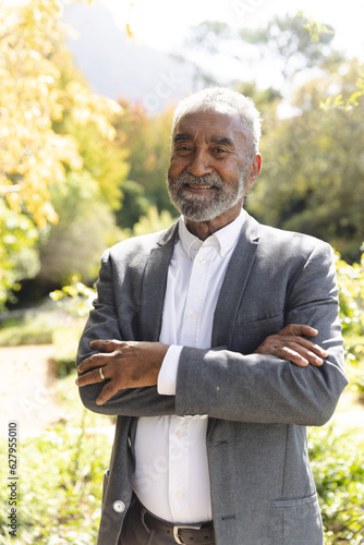 Portrait of happy senior biracial man smiling in sunny garden at home