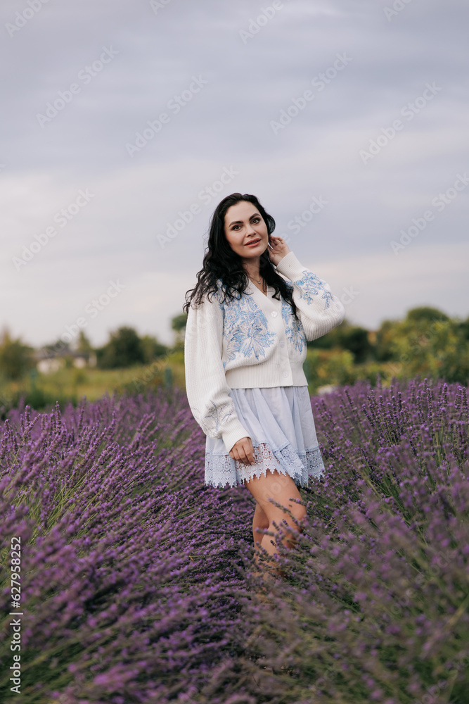 Young woman walking among blooming lavender against sky. Young woman walking among blooming lavender against sky.