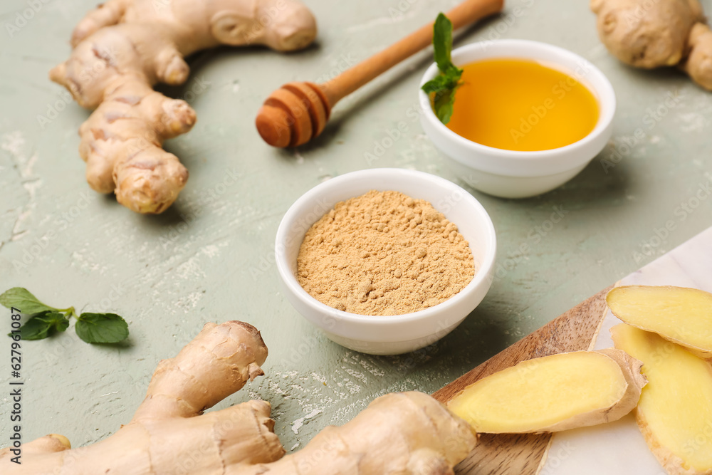 Fototapeta premium Fresh ginger roots and bowl with dried powder on grey background