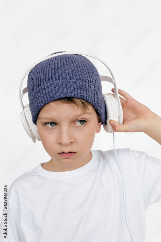 Modern portrait of young stylish boy wearing blue-gray knit cap taking off his headphones and looking away Modern portrait of young stylish boy wearing blue-gray knit cap taking off his headphones and looking away