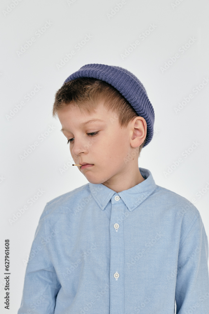 Waist up shot of melancholic boy wearing blue shirt and blue-gray knit head looking away Waist up shot of melancholic boy wearing blue shirt and blue-gray knit head looking away