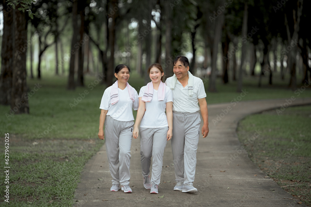 Beautiful Asian woman taking her father and mother to exercise in the park happily, with a smile. Young woman invites parents to exercise, warm family, good health. concept health care life insurance. Beautiful Asian woman taking her father and mother to exercise in the park happily, with a smile. Young woman invites parents to exercise, warm family, good health. concept health care life insurance.