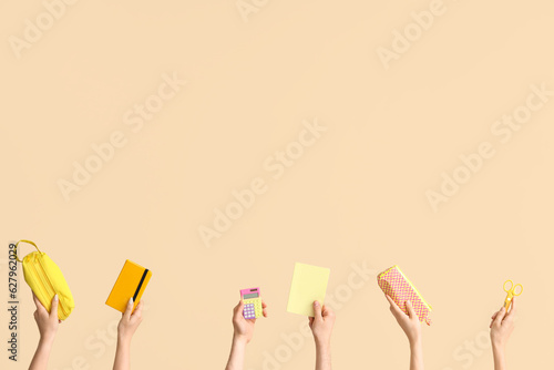 Hands with school supplies on beige background