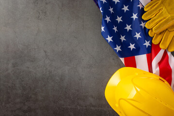 Commemorating the significant contributions of construction workers on American Labor Day. Above shot of flag, helmet and gloves on grunge textured grey concrete. Suitable for ads or text