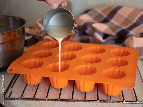 Foto Pouring the liquid batter in the silicone ridged fluted mold before baking