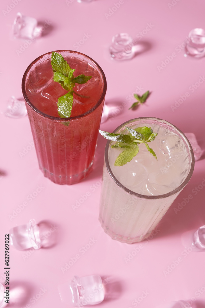 Summer lemonades with ice and mint in glass glasses top view on pink background. Summer lemonades with ice and mint in glass glasses top view on pink background.