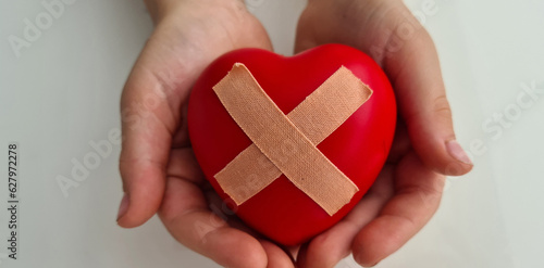Foto Child holds broken heart sealed with band-aid
