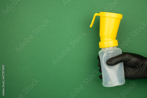 Bilde på lerret Teat dip cup for udder cow disinfection in farmer hand on green background, banner