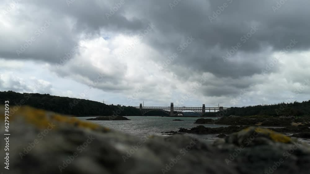 Looking over unfocused rock foreground to overcast Menai Straits Britannia bridge to Anglesey Looking over unfocused rock foreground to overcast Menai Straits Britannia bridge to Anglesey